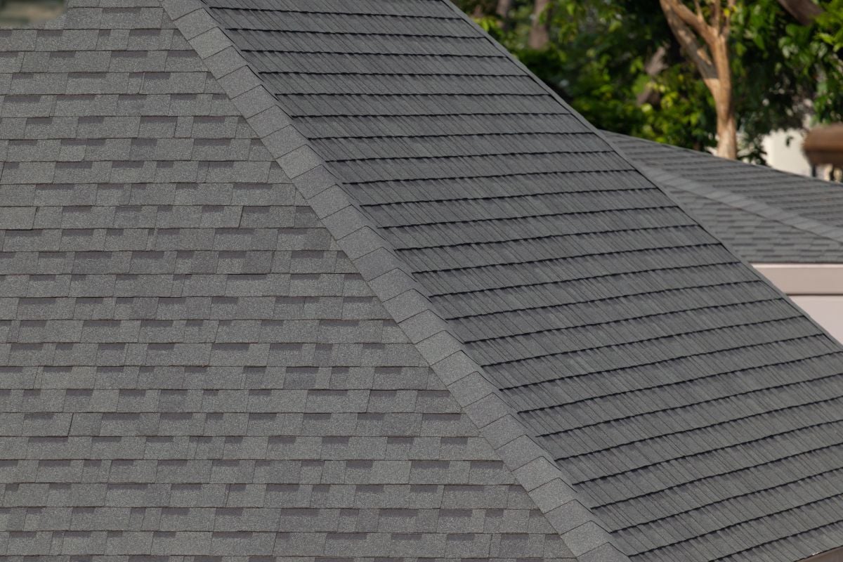 Dark gray shingles line a sloped roof with neat rows